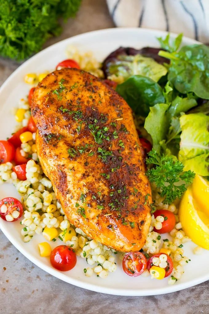 Air fryer chicken breast served with couscous and salad.