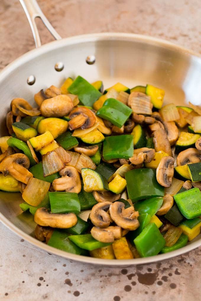 Mushrooms, zucchini and bell peppers cooked in a pan.