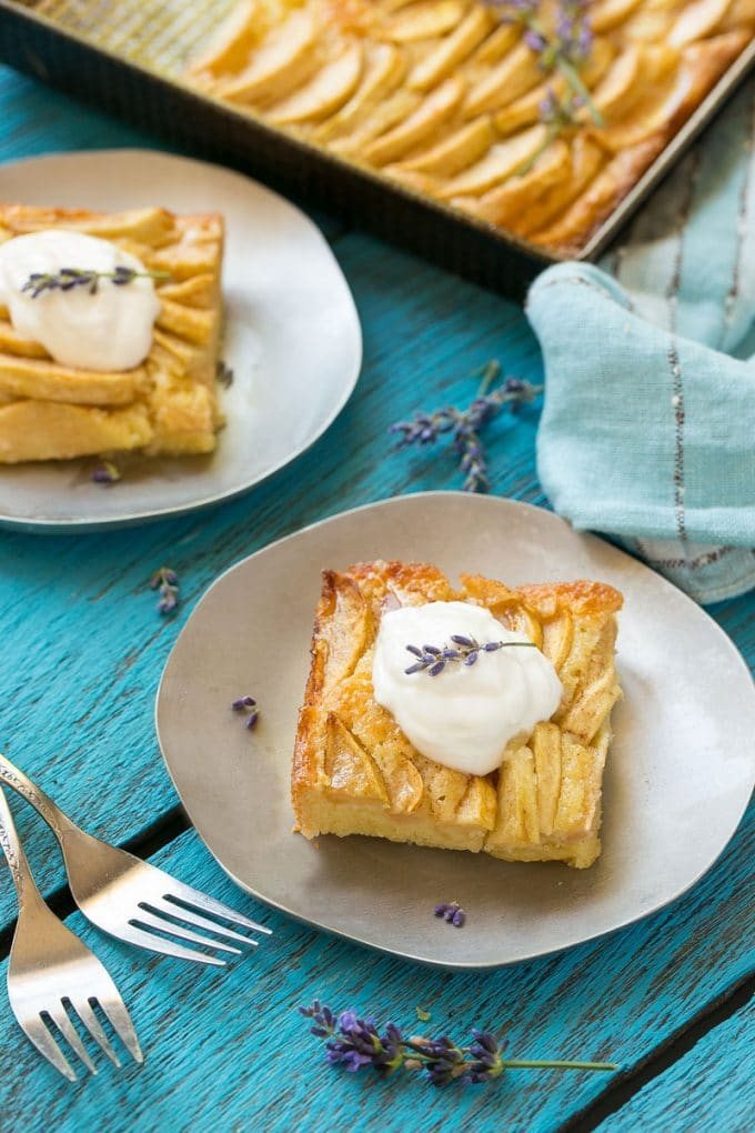 A slice of a apple cinnamon cake on a small plate with whipped cream on top.