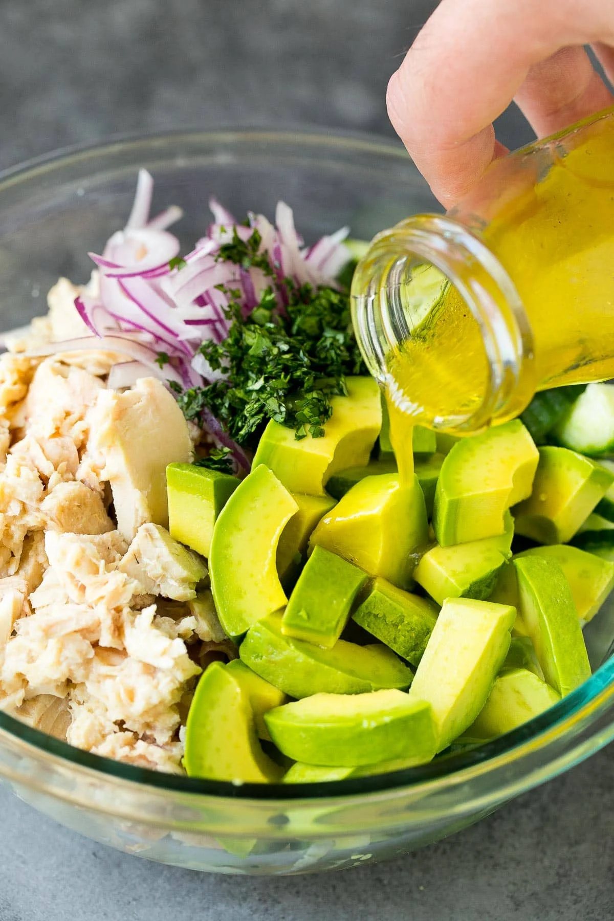Dressing being poured into tuna salad.