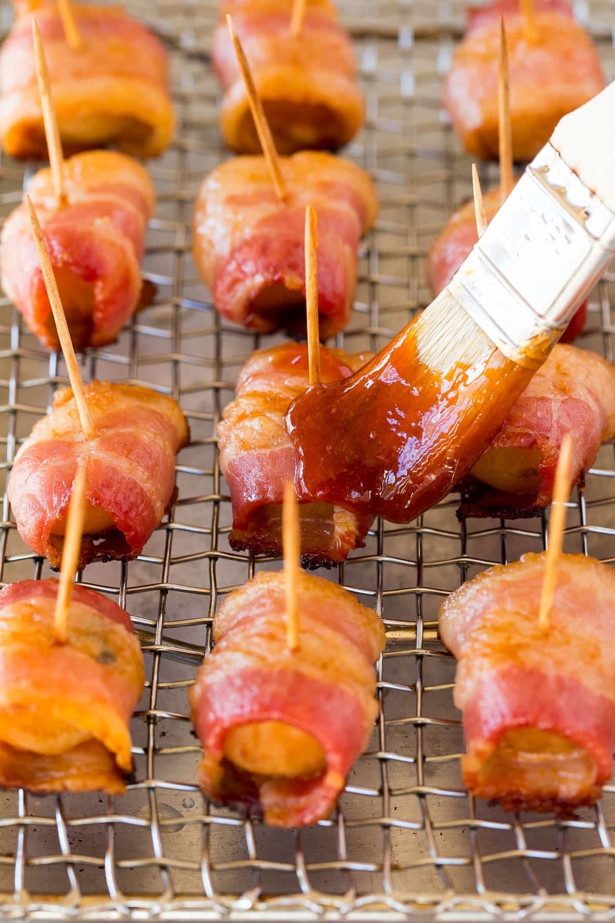 Sauce being brushed over the appetizers.