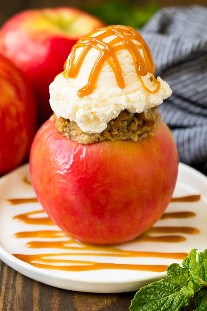 A baked apple topped with vanilla ice cream and caramel sauce.