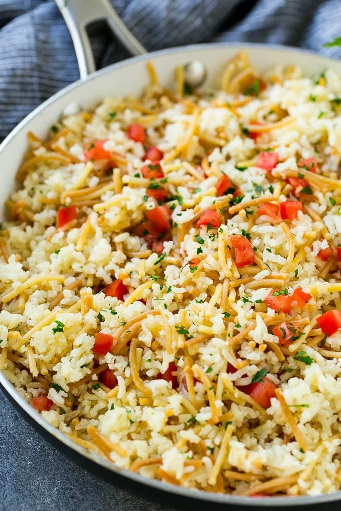 Kitchen-made rice-a-roni topped with tomatoes and herbs, all in a skillet.