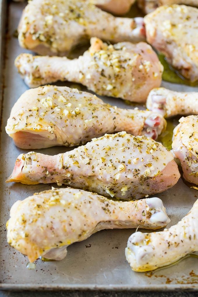 Marinated chicken legs on a sheet pan, ready to go into the oven.