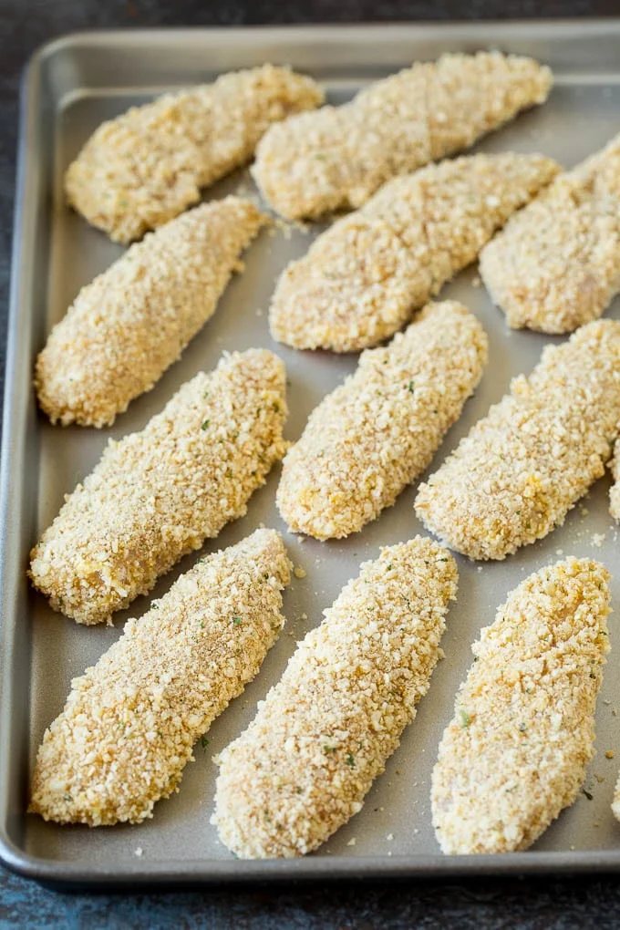 Breaded chicken fingers on a sheet pan.