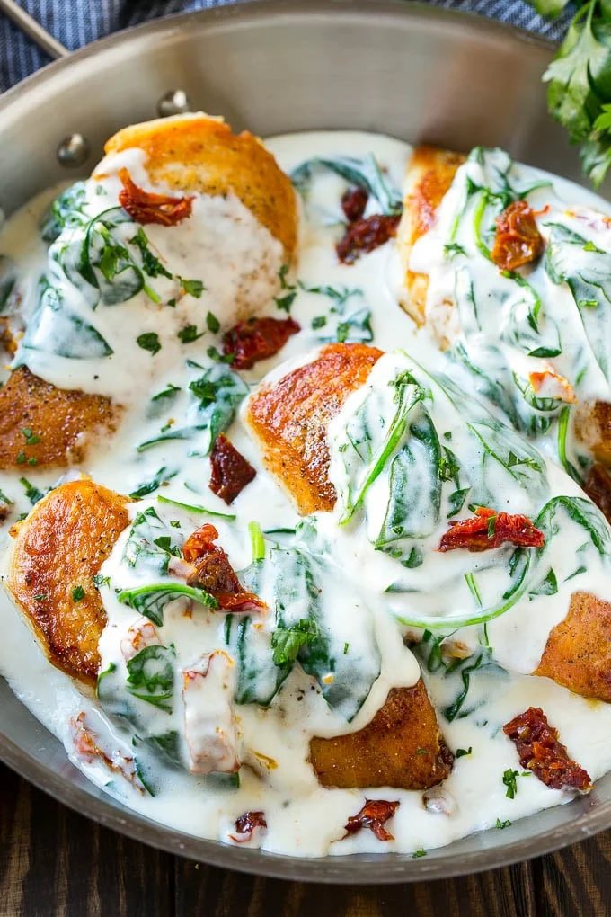 Sun dried tomato chicken covered in a silky spinach sauce in a frying pan.