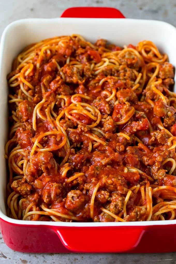 Pasta tossed with meat sauce in a dish.
