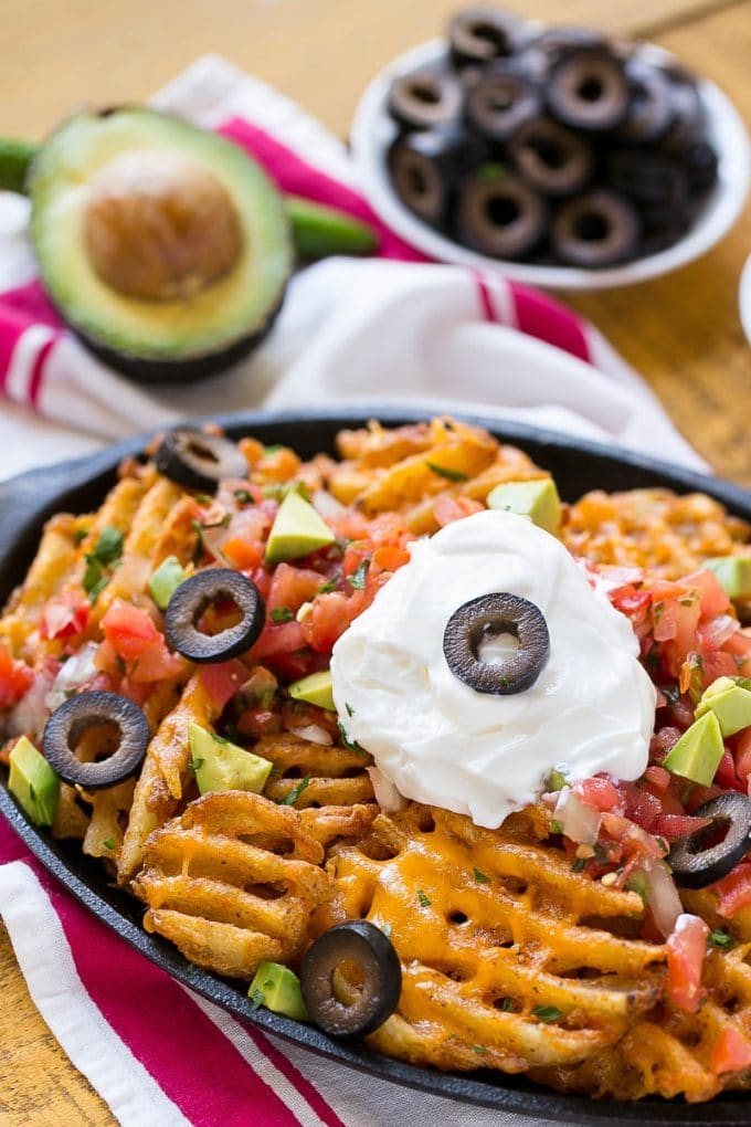 Waffle fries are smothered in nacho toppings for a fun and tasty snack.