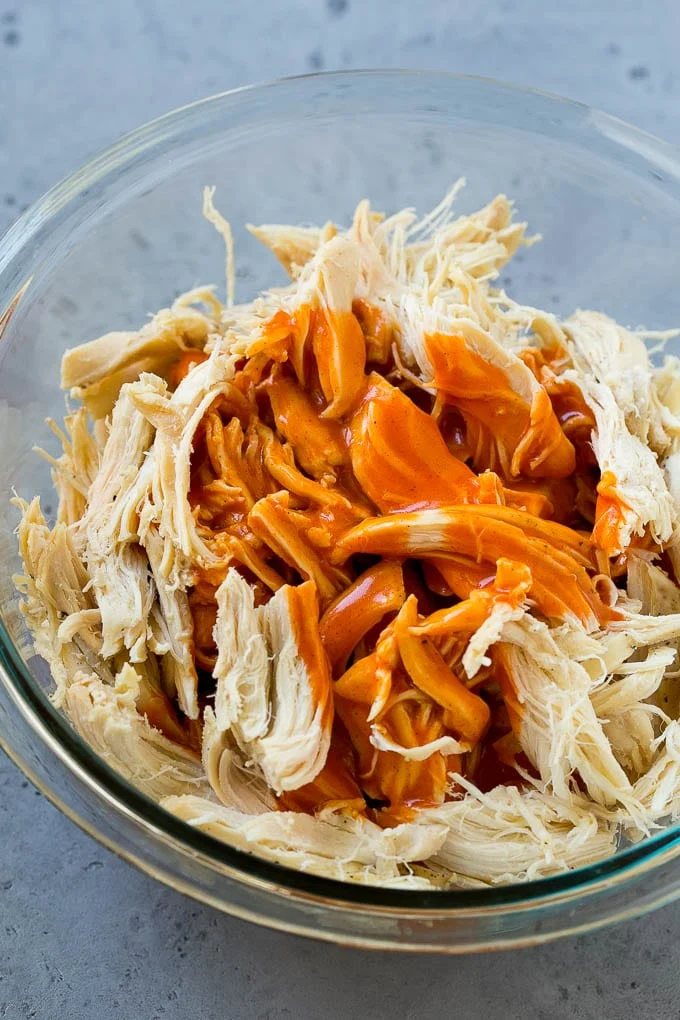 Shredded poultry in a bowl with tangy sauce.