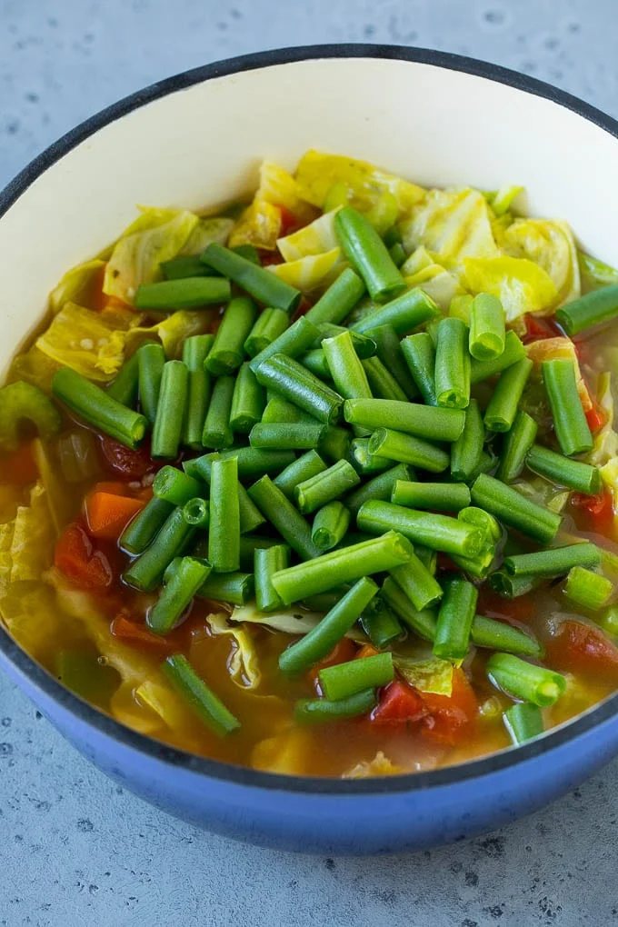 Green beans in a pot of cooked veggies.