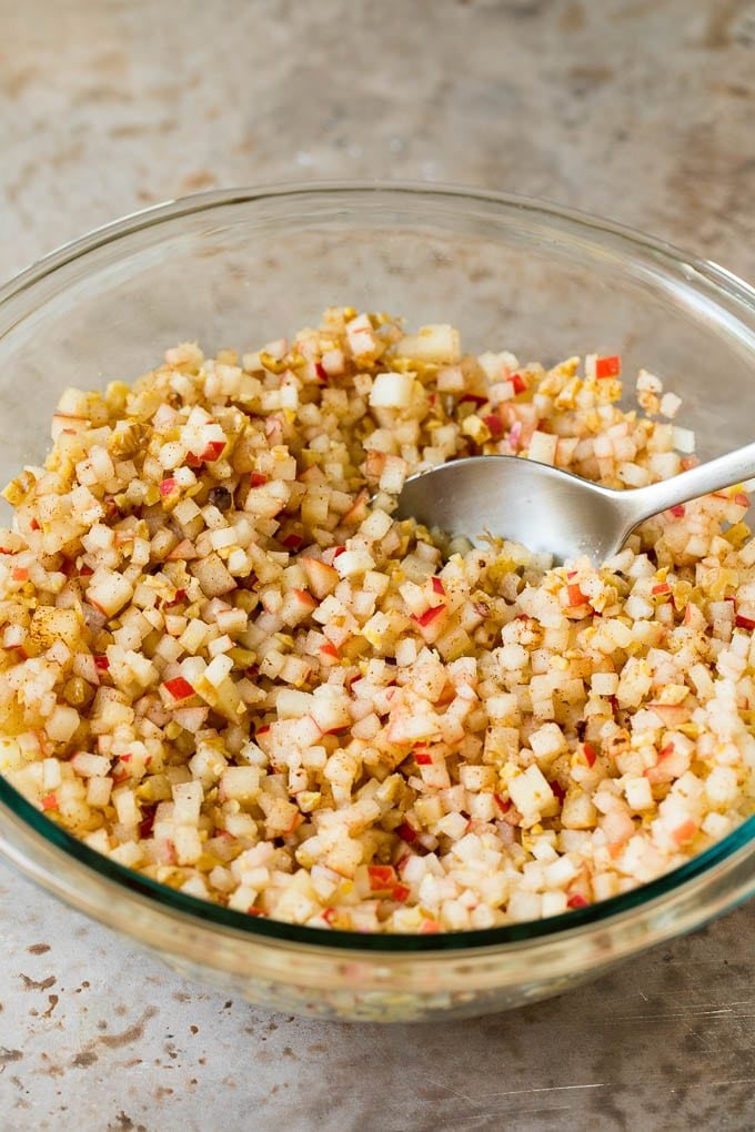 A mixing bowl filled with diced apples, cinnamon and sweetener.