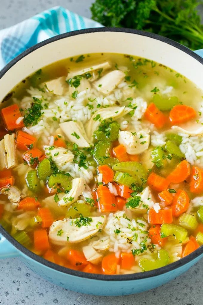 A pot of chicken and rice soup with carrots, celery, chicken breast and white rice.