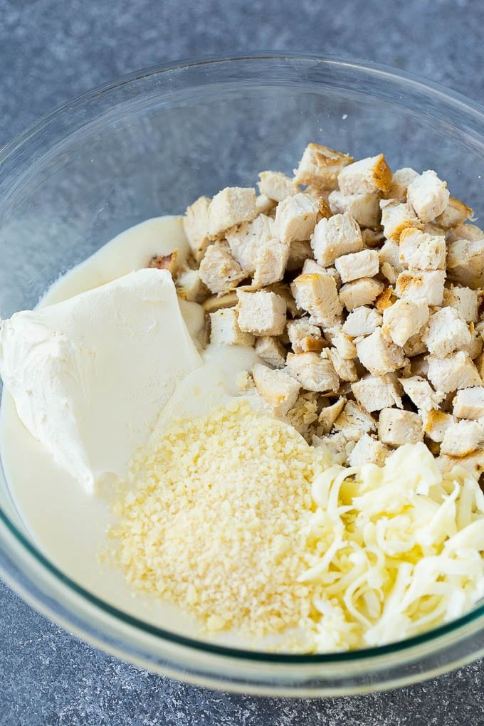 Chicken, Alfredo sauce, cream cheese, mozzarella and parmesan cheese in a mixing bowl.