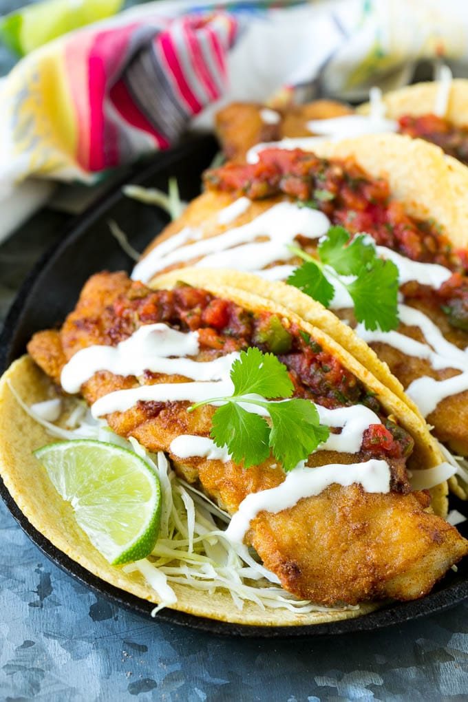 Baja fish tacos filled with crunchy fish fillets and topped with salsa and white sauce.
