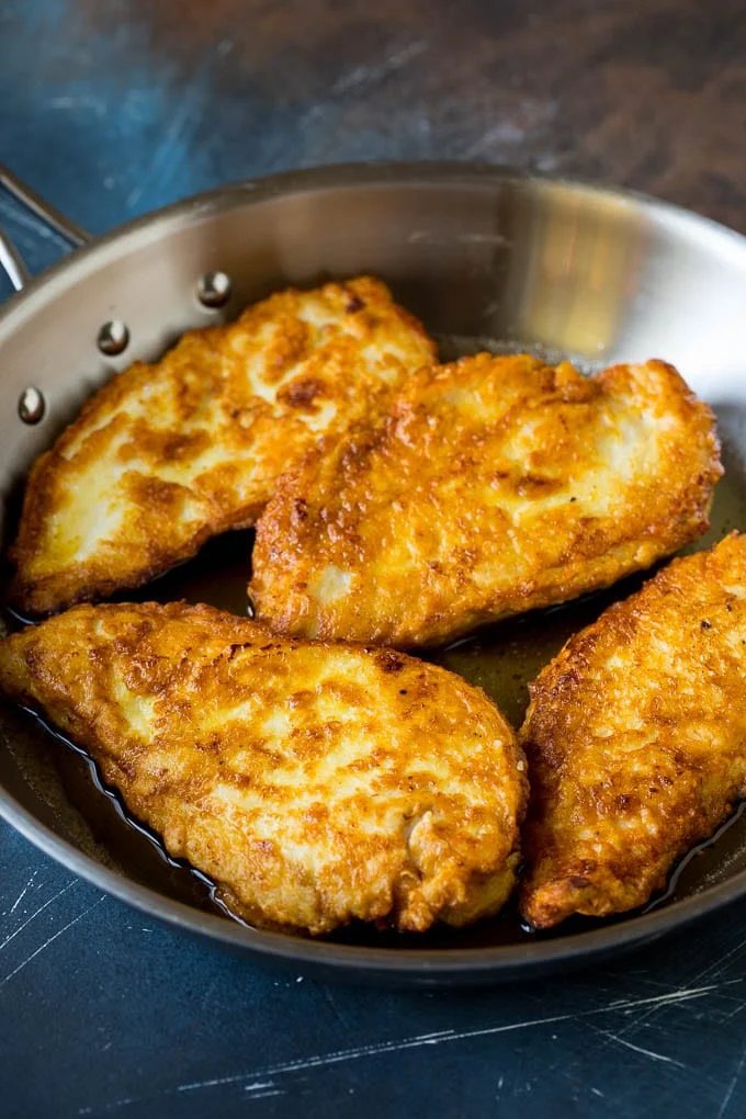 Battered and pan fried chicken cutlets in a pan.