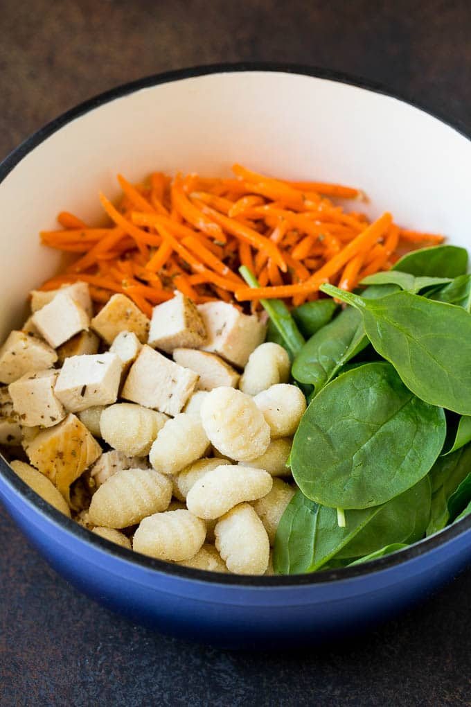 Chicken, spinach, carrots and gnocchi in a pot.
