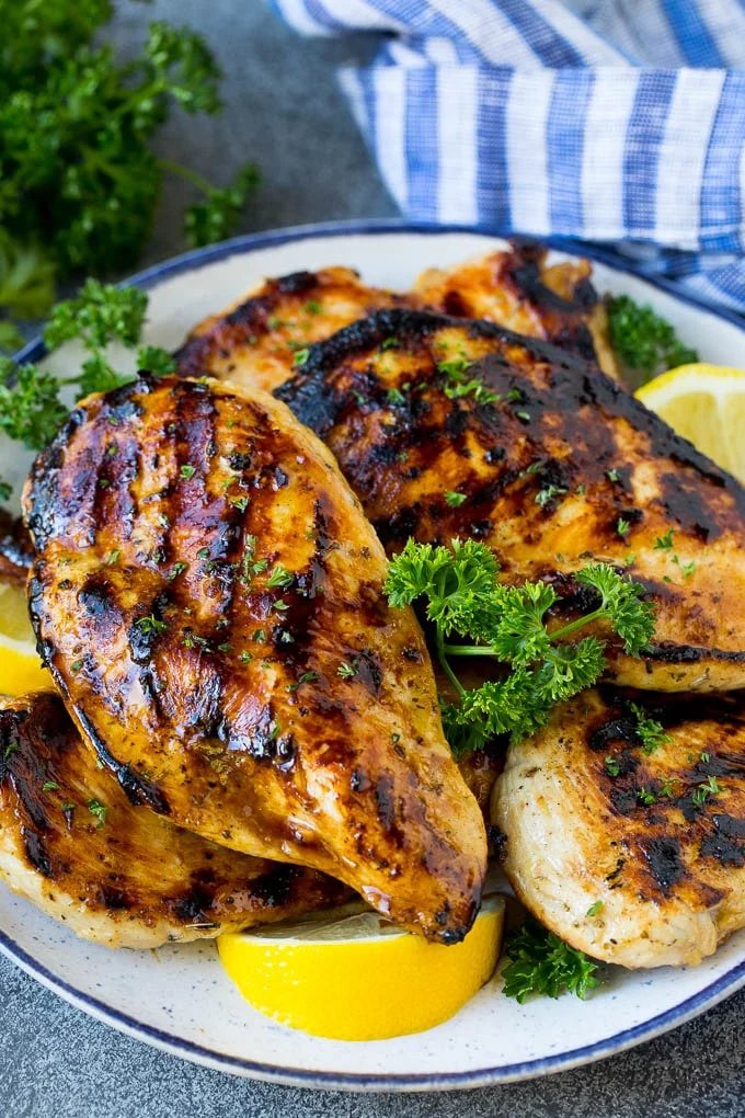 The finest chicken marinade covering grilled chicken breasts, garnished with lemon.