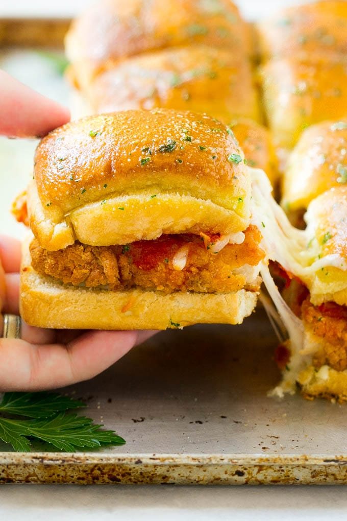 A crunchy chicken parmesan slider being pulled away by a hand.