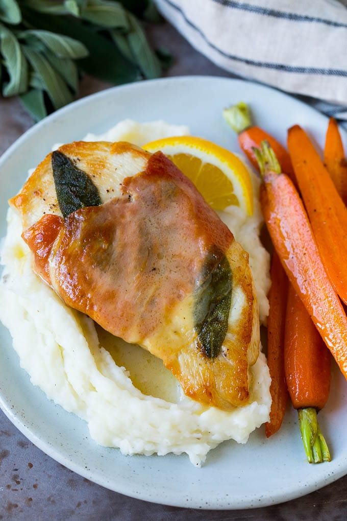 Chicken saltimbocca served over mashed potatoes with carrots on the side.