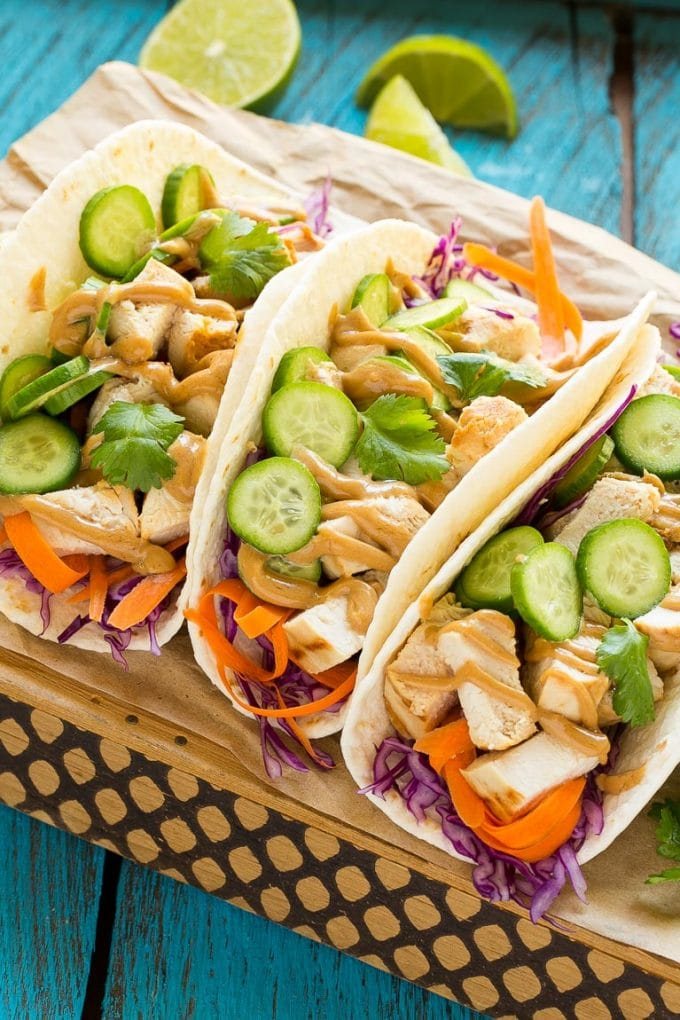 These thai chicken tacos are a quick and straightforward dinner. Coconut marinated chicken is stuffed into warm tortillas with fresh vegetables and a generous amount of kitchen-made peanut sauce.