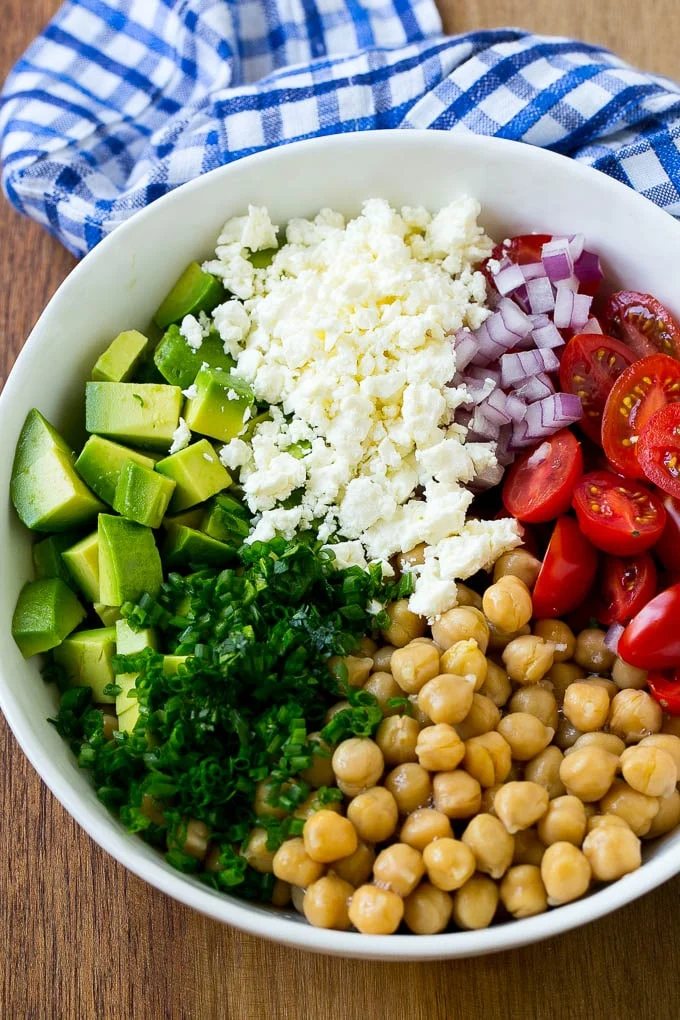 A bowl of chickpeas, avocado, feta, chives and tomatoes.