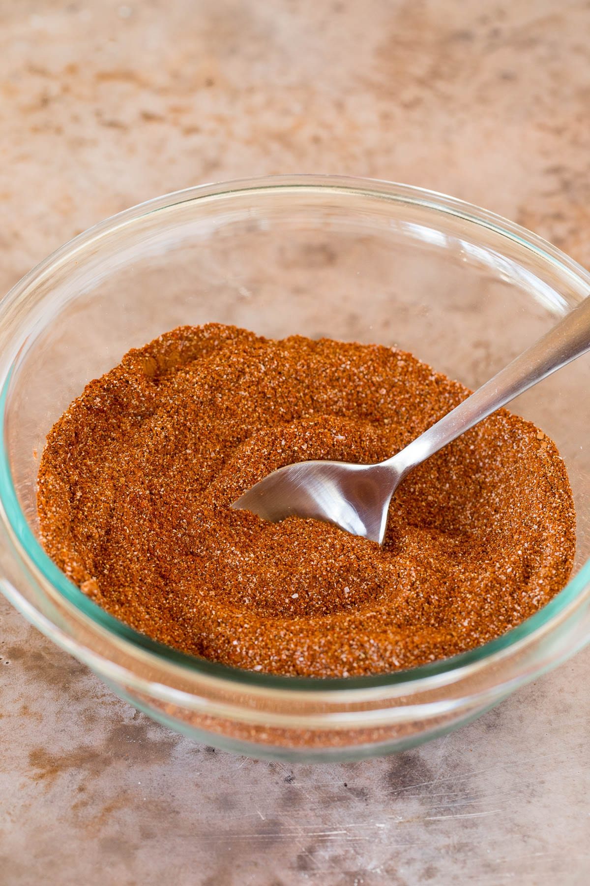 A bowl of seasoning with a spoon in it.