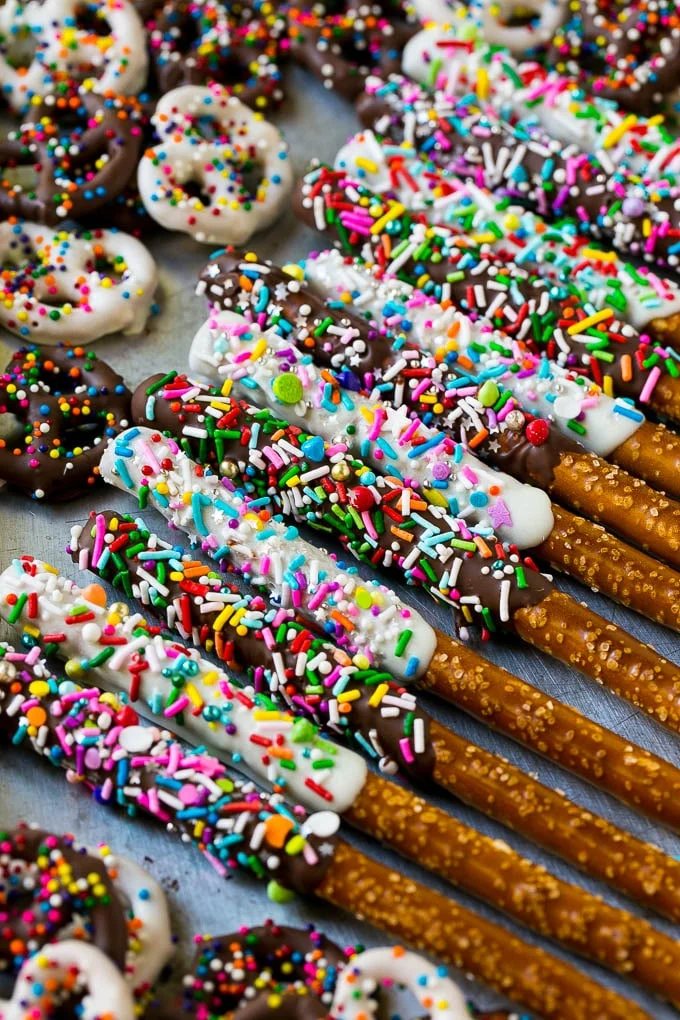A sheet pan with coated twists and rods decorated with rainbow sprinkles.