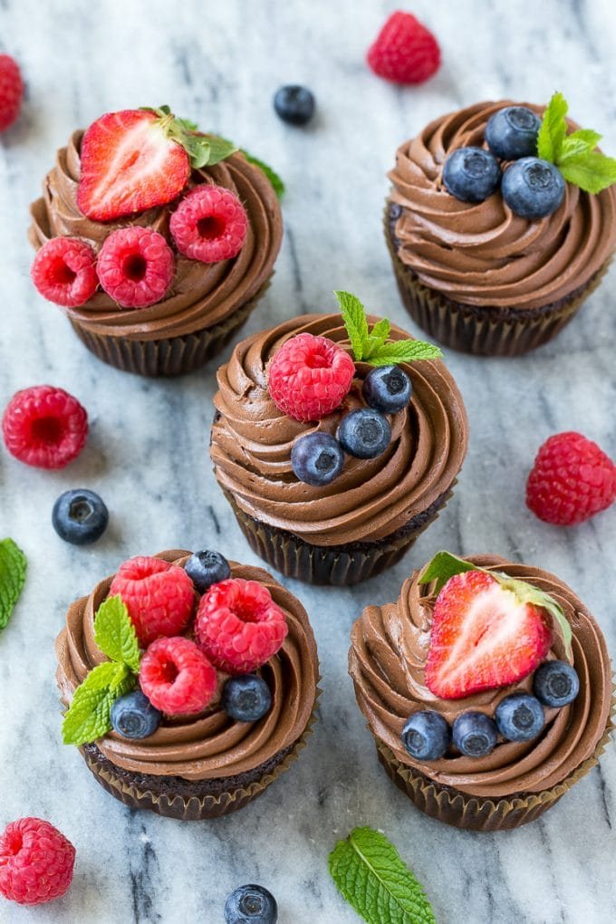 Chocolate hazelnut cupcakes topped with berries and mint sprigs.