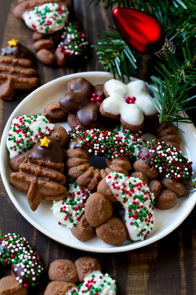 Chocolate spritz cookies coated in sprinkles on a serving plate.