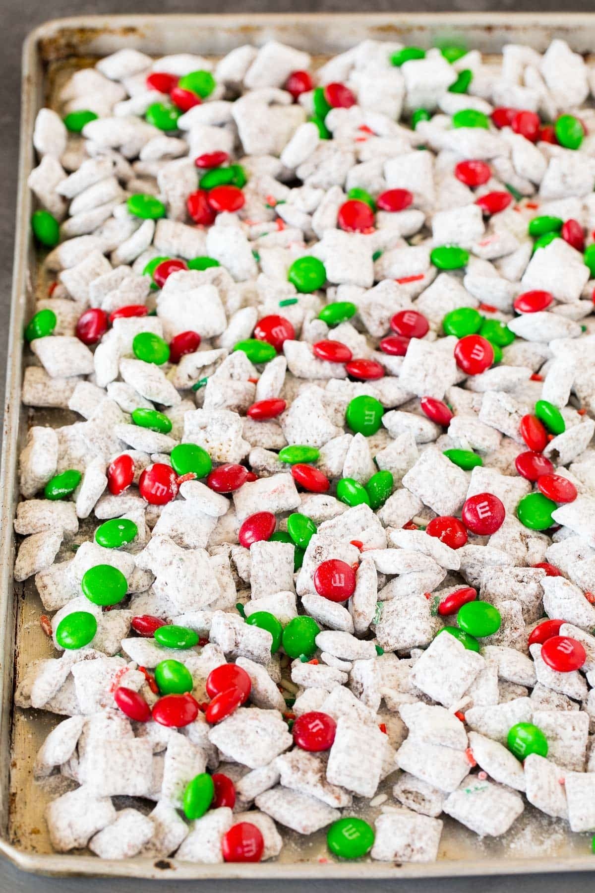 A sheet pan of Christmas puppy chow with muddy buddies, M&M's and sprinkles.