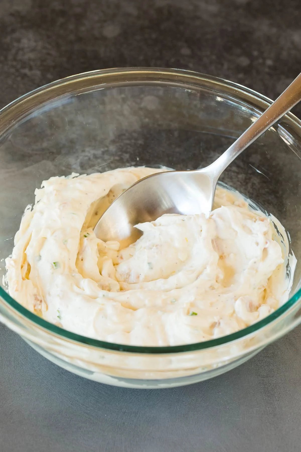 A spoon in a mixing bowl of creamy dip.