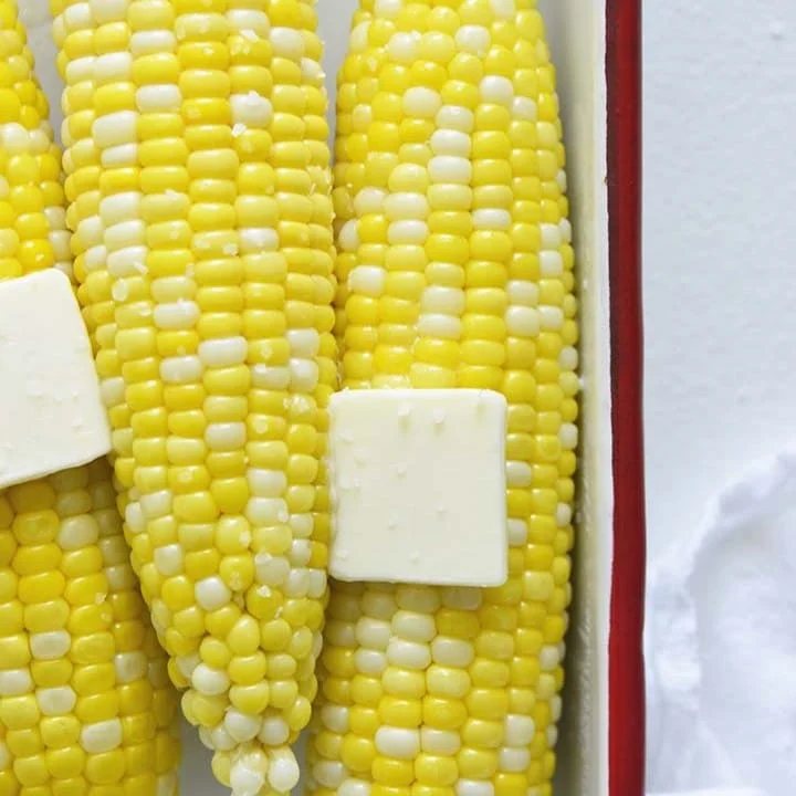 An image of microwaved corn on the cob with butter on top.