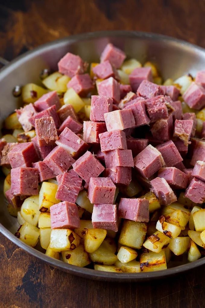 Cubed corn beef on top of cooked potatoes.
