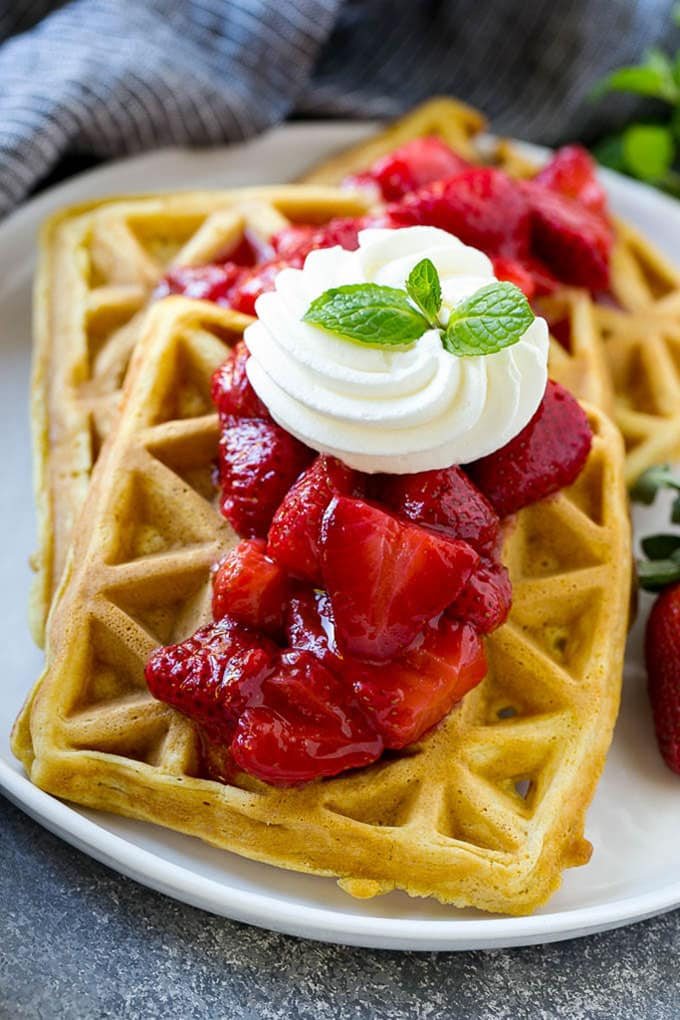 Strawberry waffles are kitchen-made waffles topped with fresh strawberry sauce and whipped cream.