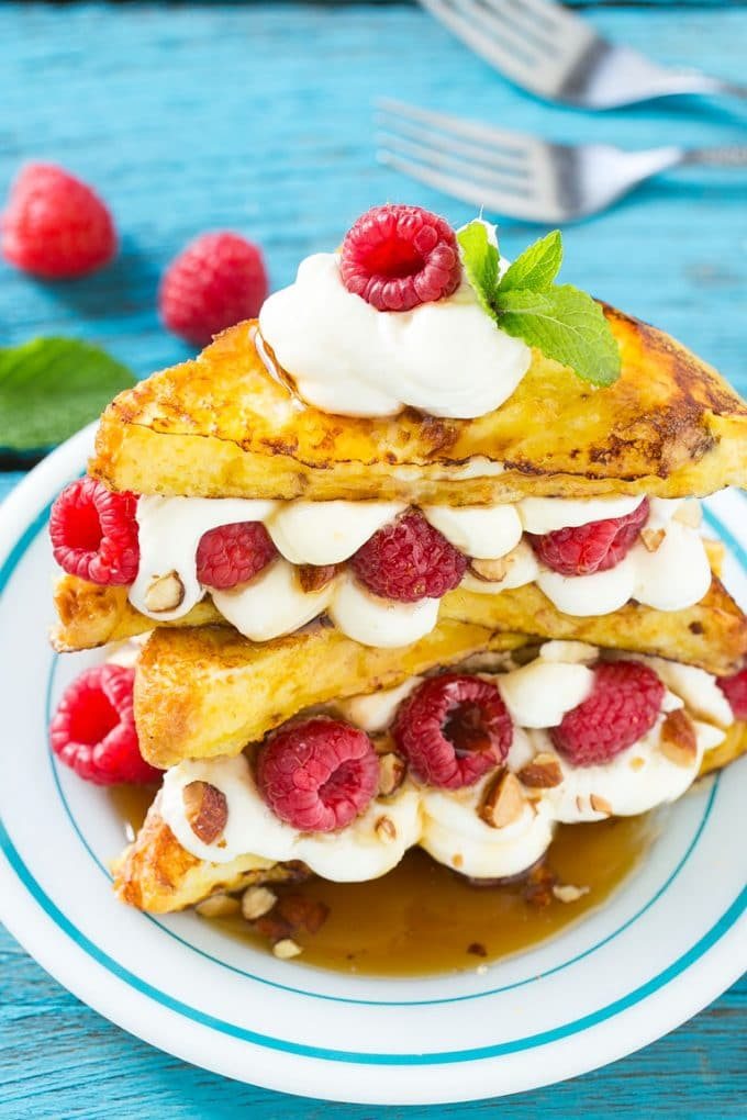 A plate of cooked brioche filled with cream cheese, berries and almonds.
