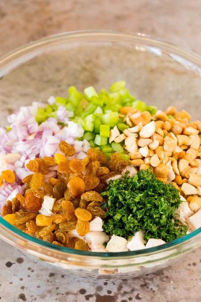 A bowl of diced chicken with raisins, cashews and vegetables.