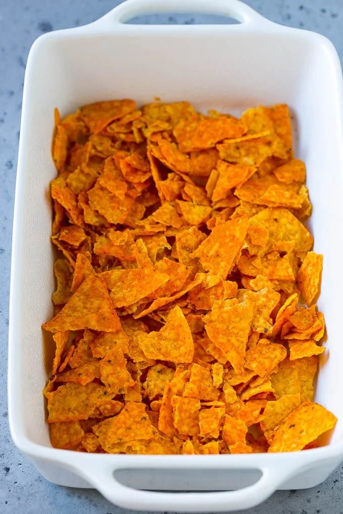 Crushed nacho chips in the bottom of a casserole dish.