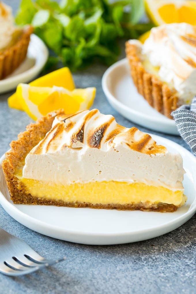 A slice of lemon meringue tart with silky lemon filling and brown sugar meringue topping.