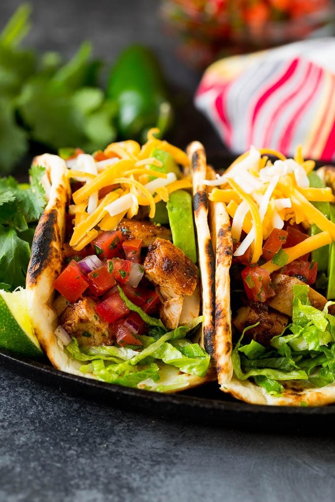 Chicken tacos topped with cheese, pico de gallo and avocado.