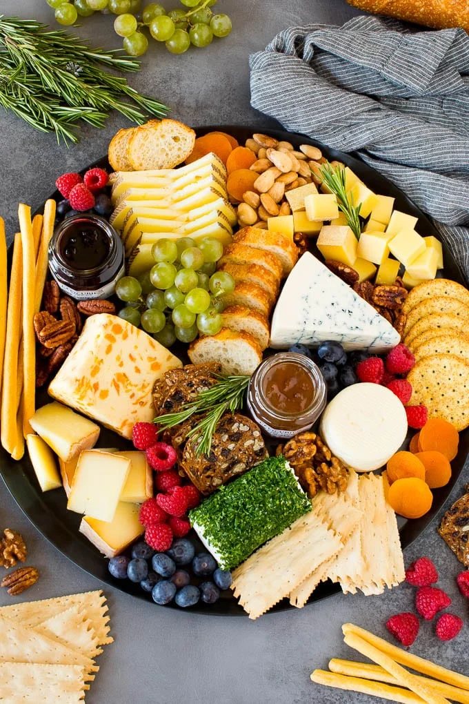 The finest cheese board with assorted cheeses, bread, crackers, fruit and nuts on a large platter.