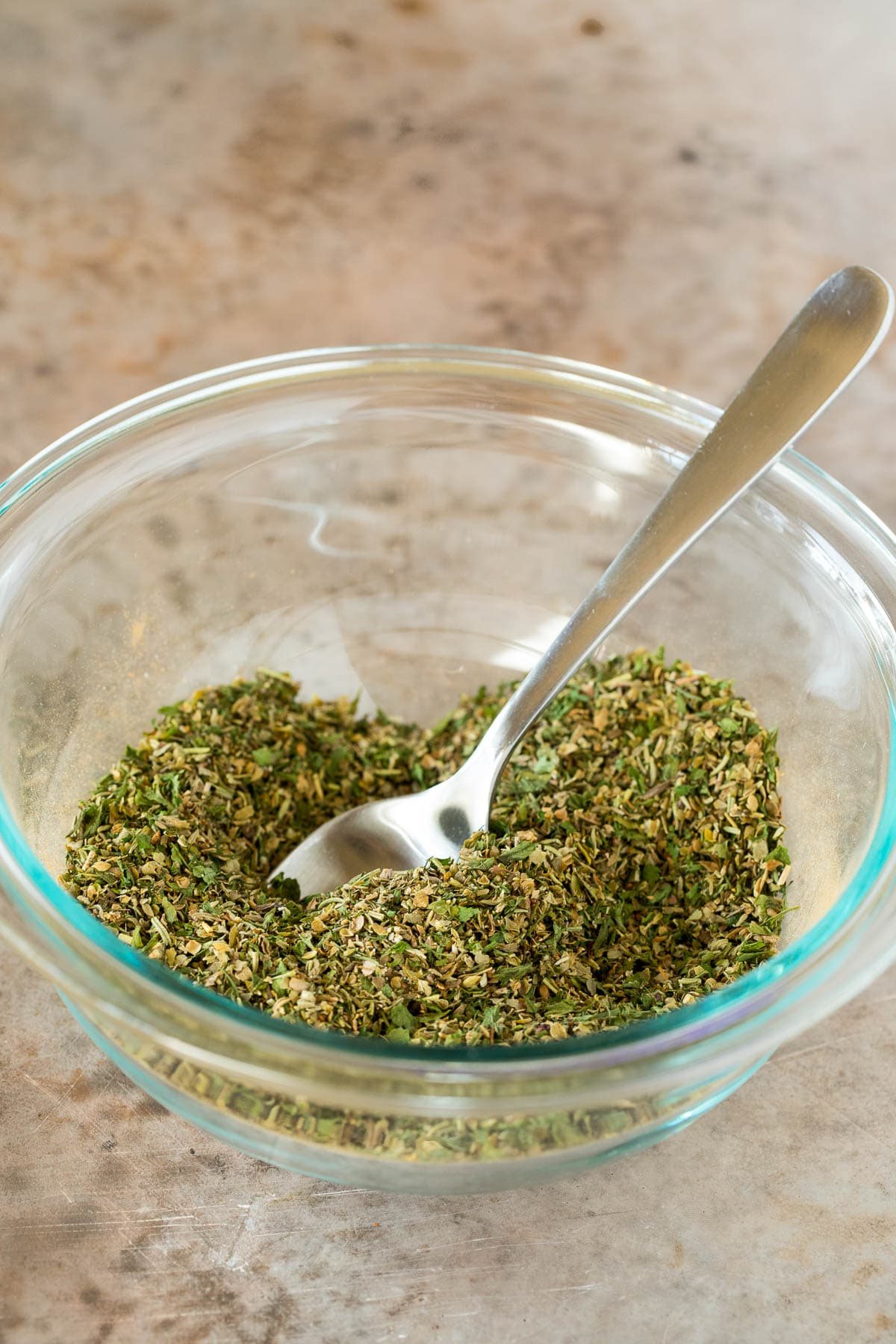 A bowl of seasoning with a spoon in it.