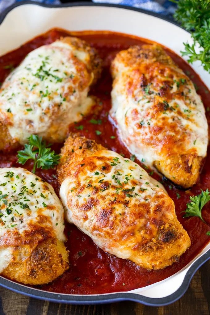 A skillet of baked chicken parmesan with crunchy chicken breasts, marinara sauce and melted cheese.