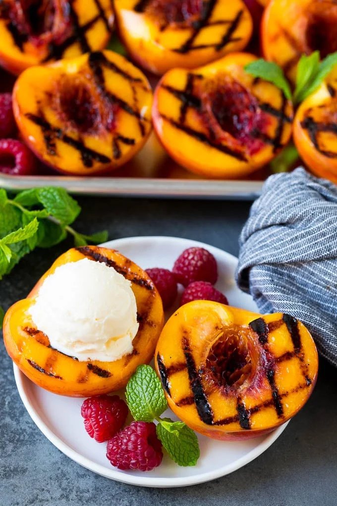 Grilled peaches topped with a scoop of vanilla ice cream.