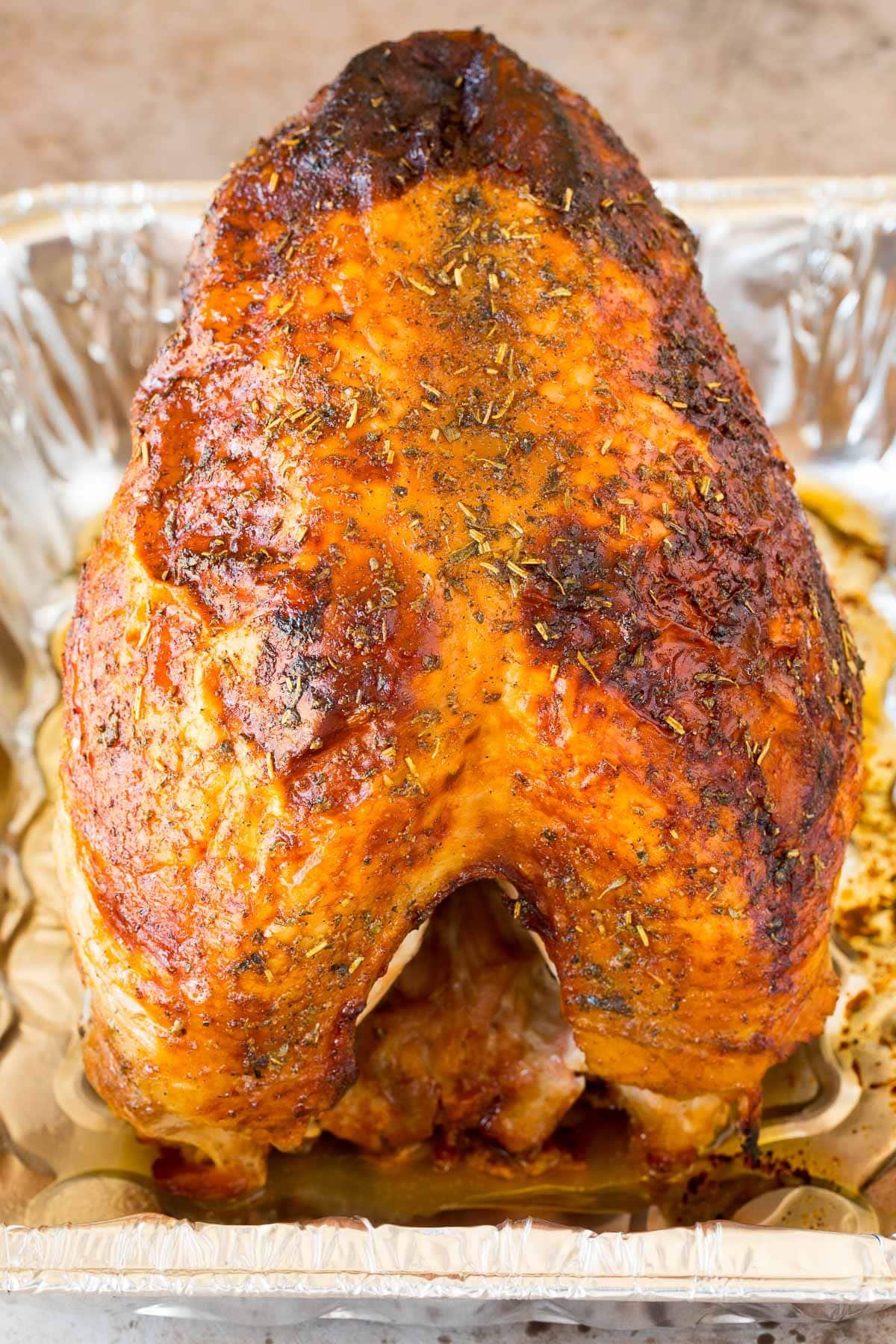 A whole grilled turkey breast in a disposable aluminum pan.