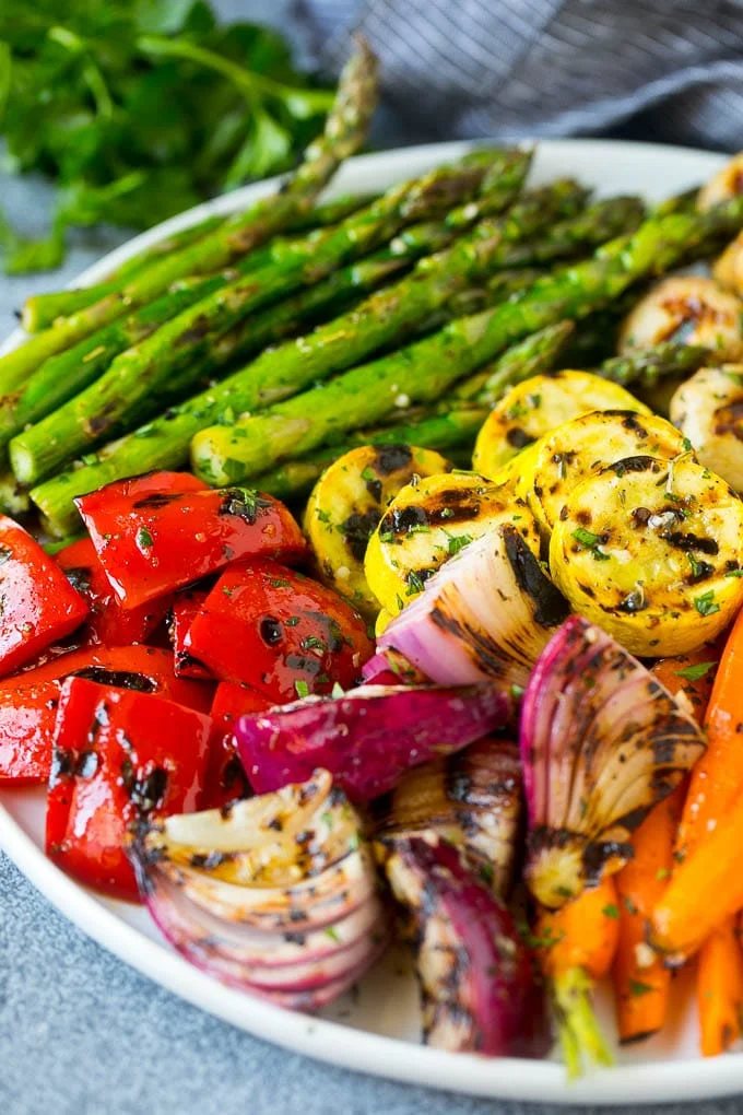 A platter of grilled veggies including peppers, onions and carrots.