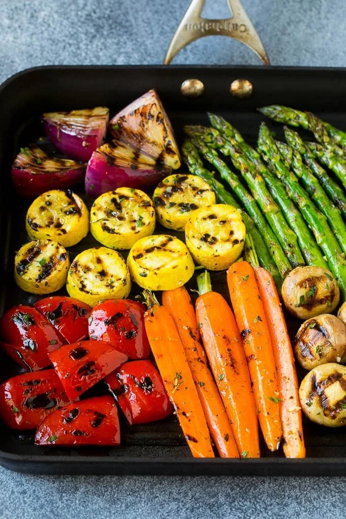 A grill pan with an assortment of vegetables cooking on it.