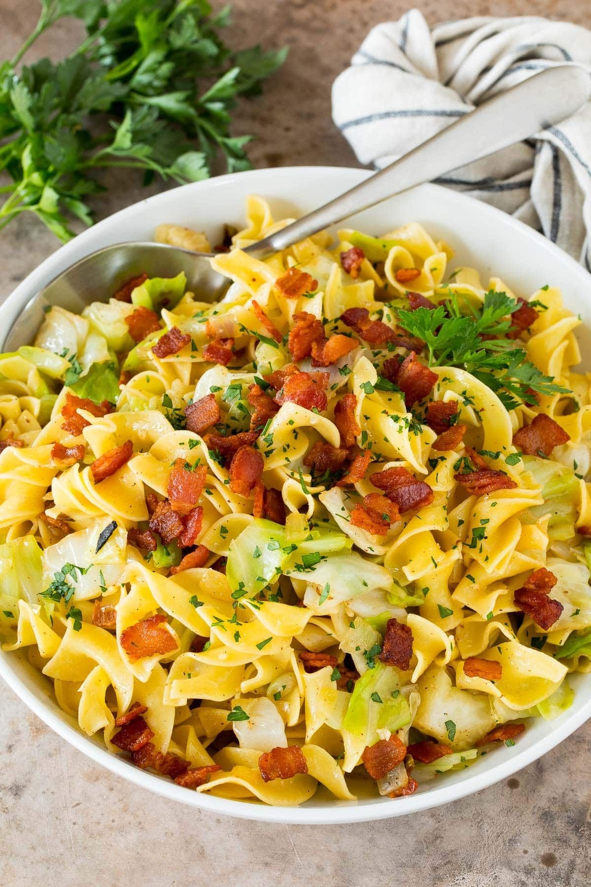 A bowl of haluski topped with bacon and parsley.