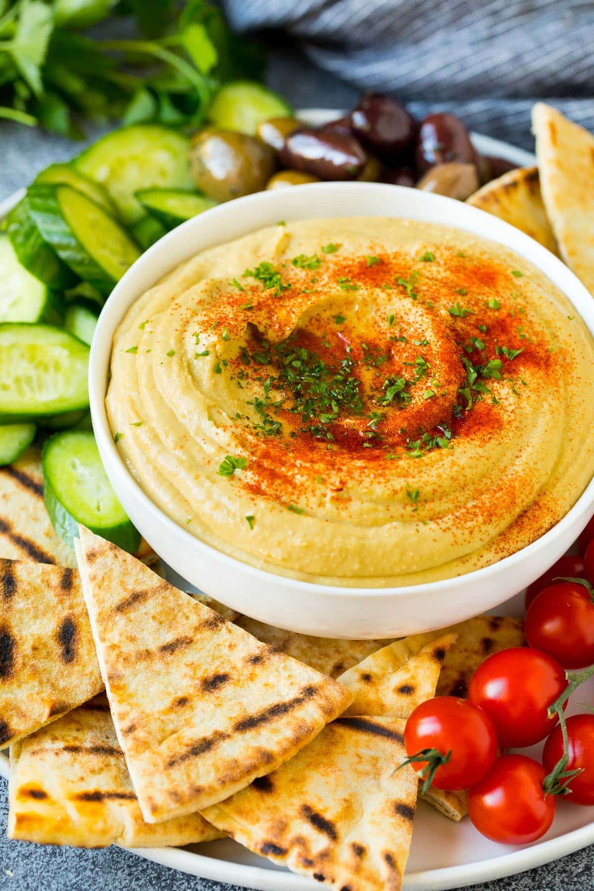 A bowl of kitchen-made hummus served with pita and vegetables.
