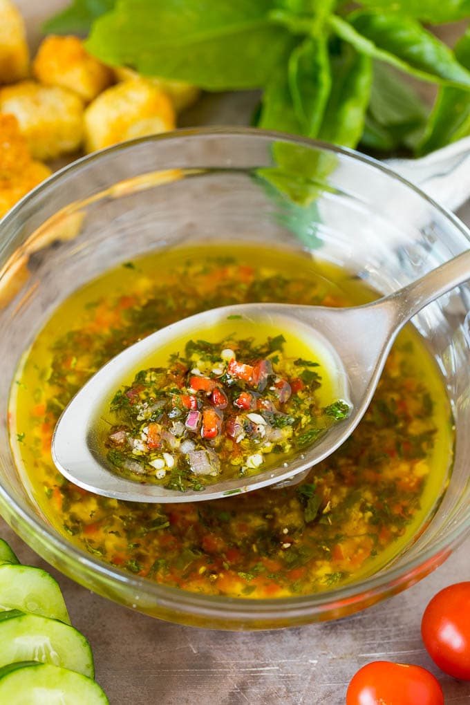 A bowl of kitchen-made Italian dressing with a spoon in it.