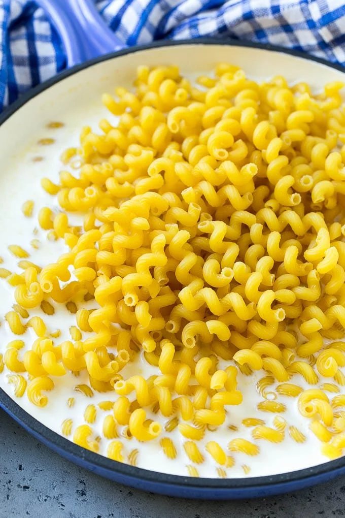 Pasta in milk with seasonings in a pan.